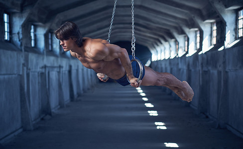 逃生演习摄影照片_肌肉英俊的男子与运动的身体做静态演习钢环在黑暗的隧道.