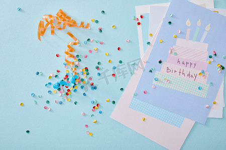 蓝色背景的生日贺卡附近彩色艳丽的五彩纸屑的顶视图