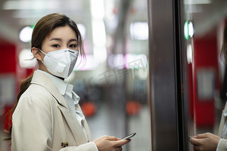 戴口罩的年轻女人站在地铁站台上