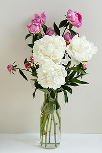 春夏饮品菜单摄影照片_简单的树冠花束，由粉色和白色的牡丹组成，装在透明的花瓶里，盖在油腻的背景上，春夏两季的花朵上