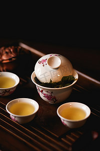 中国风描金祥云摄影照片_中国茶道。瓷盖碗，三杯中国茶和茶桌上的金蛙. 