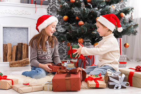 快乐的孩子在圣诞老人的帽子展开圣诞礼物
