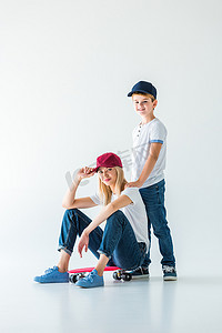 红帽摄影照片_母亲坐在滑冰和触摸红帽, 儿子站在她旁边的白色