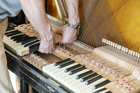 钢琴调音过程。手和调谐器工具在大钢琴上的特写。调音期间Upright钢琴的详细视图。调音的.