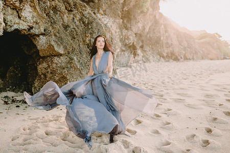新娘的肖像在蓝色婚礼礼服在海滩以日落或日出颜色.
