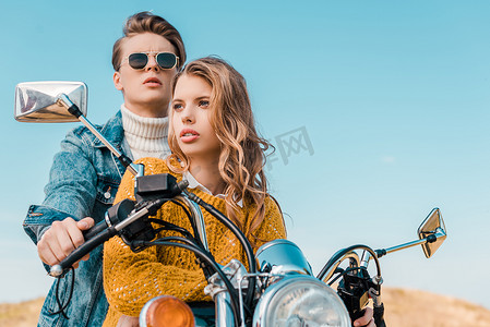 快乐情侣坐在摩托车上对抗蓝天 