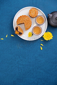 蓝色背景简约摄影照片_中秋节蓝色背景的简约月饼，创意食物设计理念，顶视图，平铺，复制空间.