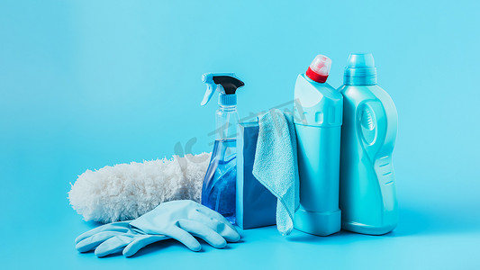 洗衣粉摄影照片_在蓝色背景下关闭除尘器、橡胶手套、清洗液、洗衣粉、抹布和洗衣液的全景图 