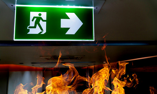 消防疏散图摄影照片_绿色消防逃生标志挂在办公室的天花板上.