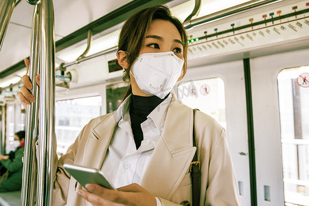 上下班摄影照片_戴口罩的年轻女人乘坐地铁