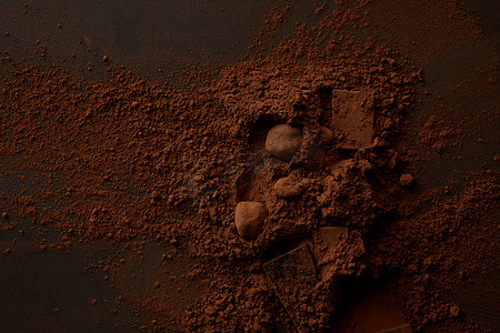 在黑暗背景下的美味巧克力片和美味可可粉的顶级视图 