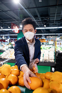 水果超市促销摄影照片_戴口罩的青年男人在超市挑选水果