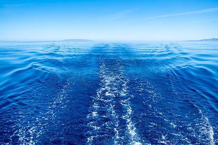 Boat wake, prop wash foam, blue calm sea and clear sky background, view from the ship. Sailing in Aegean sea