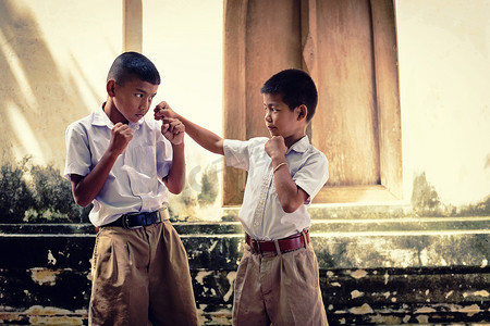 两个穿着校服的亚洲男孩正在打拳击, 老 w