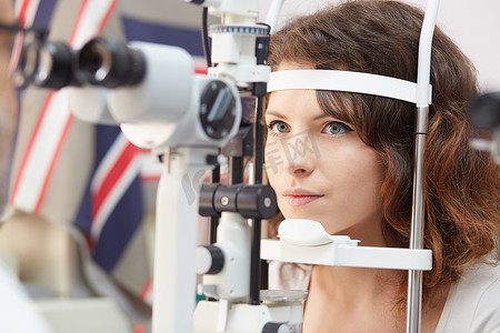 漂亮的女人望眼试验机在眼科医生的实验室里的浓度