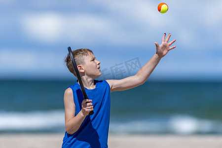 sport摄影照片_Young boy playing tennis on beach. Kids sport concept. Horizontal sport theme poster, greeting cards, headers, website and app