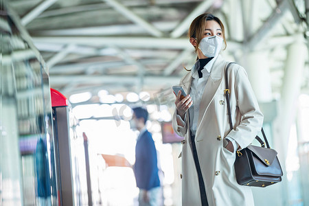 上下班摄影照片_戴口罩的年轻女人站在地铁站台上