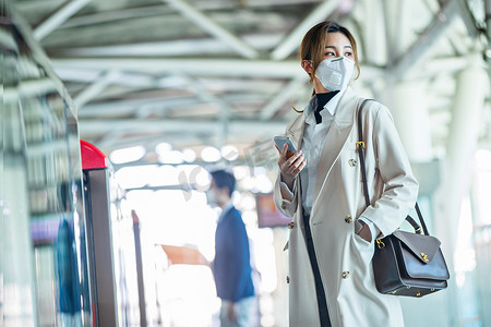 戴口罩的年轻女人站在地铁站台上