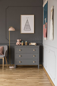 真正的照片, 一个灰色的橱柜与装饰品站在一盏灯, 扶手椅和墙壁与海报在宽敞的婴儿室内饰