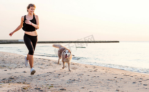 young caucasian female playing with siberian husky dog on beach during sunrise