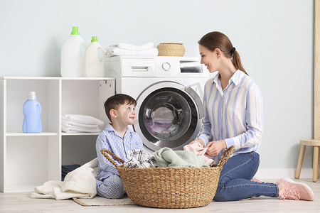 年轻女人和她的小儿子在家里洗衣服