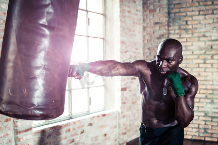 冲孔沉重的包在健身房里的黑人拳击手