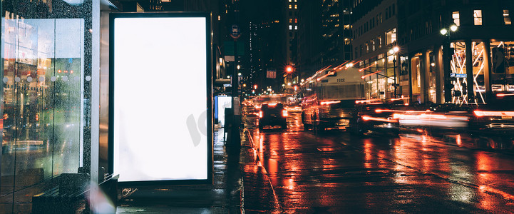 喷绘广告摄影照片_雨夜公交车站广告牌,空白复制空间屏幕,用于广告或宣传内容,空装灯箱信息,空白显示在城市街道与灯光
