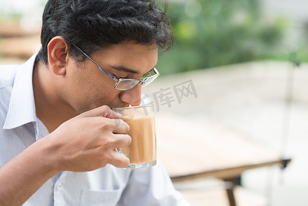 印度商人喝着一杯热牛奶茶 