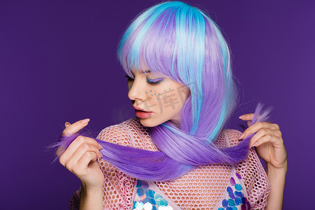 美丽的时尚女孩摆在紫罗兰色假发与星星在脸上, 孤立在紫色