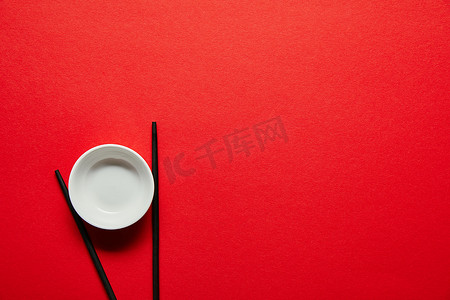 红色背景下被安排的筷子和空的碗的上部看法
