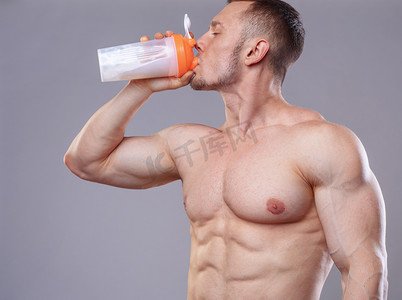 Athlete man drinking protein over grey background