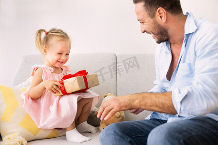 女孩抱着摄影照片_兴奋的女孩抱着礼物和爸爸坐在一起