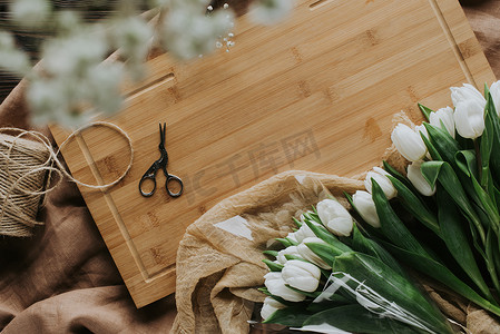 3月8日木制木板上的白色郁金香、剪刀和麻线的顶部视图