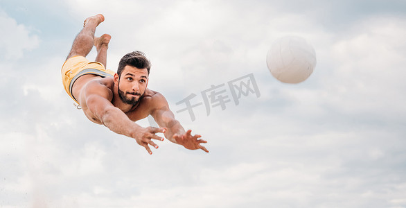 新店开业空前钜惠摄影照片_英俊的年轻人跳球, 而在多云的天空前打沙滩排球