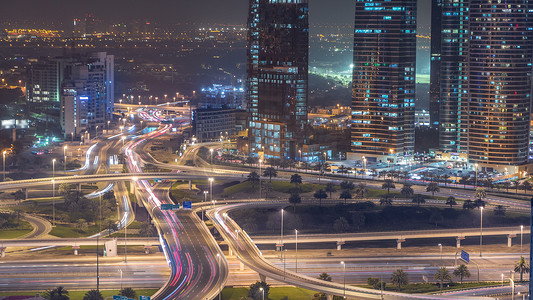 滨海区摄影照片_在一个大城市的夜晚 timelapse 的道路交叉路口的鸟瞰图。阿联酋迪拜滨海区城市景观与汽车和摩天大楼.