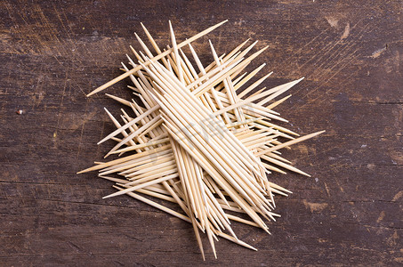 piled摄影照片_Many toothpicks tightly piled together facing different directions on dark wooden surface
