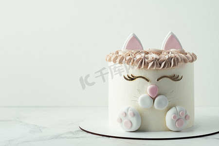 冰淇淋蛋糕当礼物摄影照片_生日蛋糕用乳胶猫耳朵、爪子和脸装饰着白色奶油奶酪泡沫。给一个白种人小女孩的惊喜蛋糕