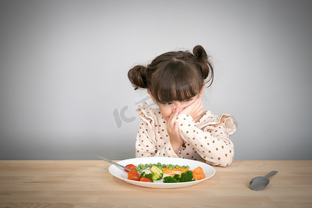 拒绝戏言摄影照片_营养与健康的饮食习惯为孩子理念。孩子们不喜欢吃蔬菜。小可爱的孩子半种族女孩拒绝吃健康的蔬菜.