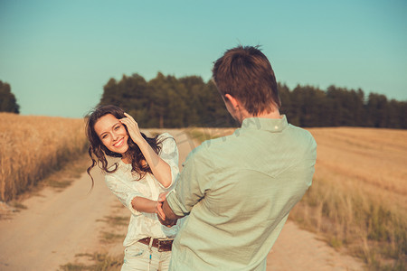 Young couple in love outdoor.in summer in field.Couple hugging.Young beautiful couple in love staying and kissing on the field on sunset. Soft sunny colors. Beautiful couple lying on the glass