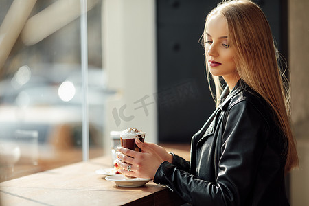 cappucino摄影照片_漂亮女孩拿着一杯可口的咖啡和扎瓦尔金眼镜。太阳
