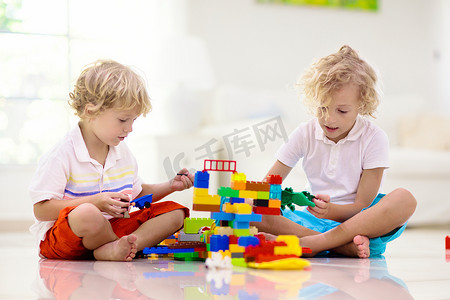 孩子们玩五颜六色的玩具块.孩子们玩塑料砖。小男孩在建造塔楼和宇宙飞船。儿童教育玩具。幼儿园或幼儿园的教室。孩子在家里.
