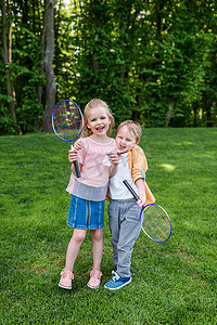 可爱的快乐的孩子举行羽毛球拍和羽毛球在公园 