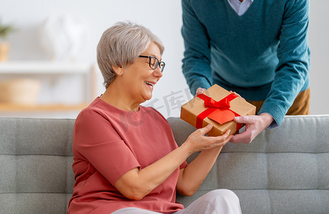 老两口在情人节。一位快乐、和善的老年妇女在收到丈夫的礼物时面带微笑.