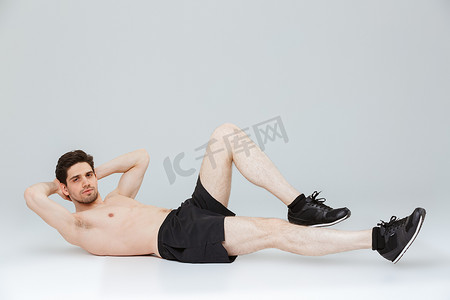 一个集中的年轻半裸运动员的肖像做 abs 演习隔离灰色背景