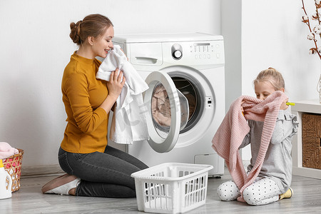 年轻女子和她的小女儿在家洗衣服