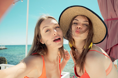 两个微笑使自拍照的海滩上的年轻女性