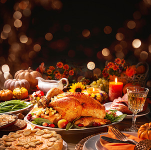 感恩节一路有你摄影照片_感恩节晚餐。用覆盆子装饰的烤火鸡，放在用南瓜、蔬菜、馅饼、鲜花和蜡烛装饰的乡村风格的桌子上