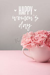 粉红色康乃馨花在杯上灰色的背景与快乐的妇女天字