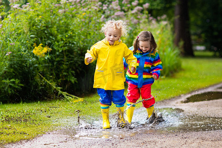 孩子们在雨中玩和水坑在秋天
