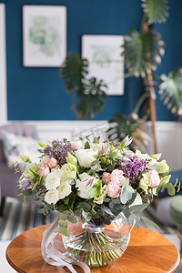 阳光明媚的春日清晨在起居室里。在木桌上的玻璃花瓶里, 美丽的鲜花花束。专业花店的工作.